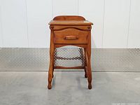 Front view of walnut stained side table showing drawer and legs
