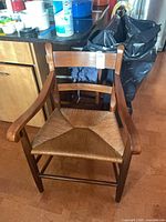 Front view of brown wood accent chair showing woven rush seat and slatted back