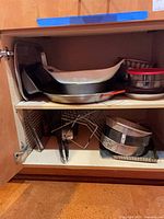 Cabinet view showing stacked bakeware items and wire rack