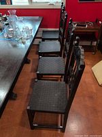 Side view of three matching dark wood dining chairs beside table