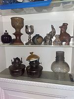 Full view of three display shelves showing all ceramics, figurines, lamp fonts and glass globe