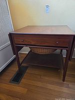 Table front view showing drawer, wicker basket, tapered legs