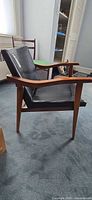 side view of wood lounge chair with black vinyl seat/back