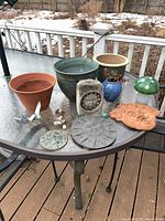 Group shot of all planters, plaques, glass mushroom, and small ornaments on patio table