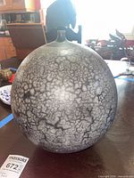 Front view of spherical raku-fired vase showing overall form and finish