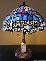 Full view of lamp illuminated showing stained glass shade and bronze-tone base