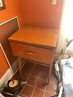 Front view of closed wooden sewing cabinet on tapered legs