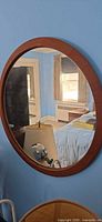 Front view of round teak wall mirror on blue wall