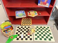 Overall lot showing chess mats, checkerboard, Chinese checkers board, atlas, blocks basket