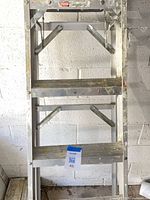 Full view mid-section of aluminum step ladder with paint wear