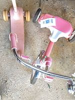 Top view of tricycle handlebars, bell, pink grips and scooter deck