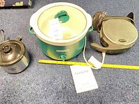 All three appliances side by side with manual and tape for scale