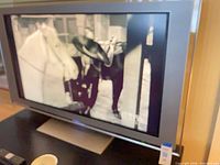 Front view of Sony 46-inch TV powered on, showing silver bezel, integrated side speakers, tabletop stand