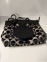 Front view of Coach signature canvas tote showing pattern, leather patch and handles