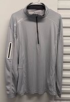 Front view of the Columbia Golf light grey long-sleeve quarter-zip pullover shirt on hanger