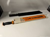 Both machetes laid out with sheath and packaging