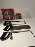 Lot overview showing three hand saws and two packaged circular saw blades