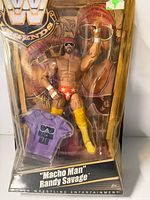 Front view of sealed Macho Man Randy Savage action figure in clamshell showing figure and purple T-shirt accessory