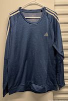 Front view of blue Adidas ClimaWarm pullover on hanger