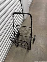 Full view of black wire shopping cart against storage unit wall