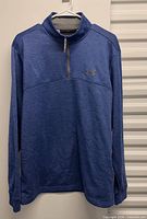 Front view of blue Under Armour quarter-zip pullover on hanger