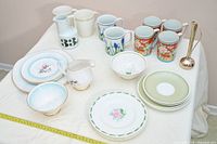 Overall view showing all assorted dinnerware, mugs, pitchers and bud vase
