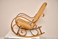 Side view of bentwood rocking chair showing curved frame, cane seat and back