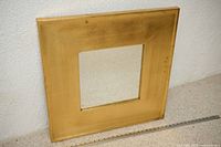 Front view of square gold gilt mirror showing frame and central glass