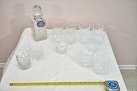 Full lot view showing decanter, stopper, label and grouped glasses beside measuring tape