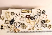 Entire lot of approx. 31 bracelets laid out on table with ruler for scale