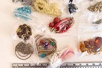Overview of multiple bagged jewelry pieces next to ruler