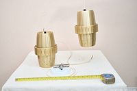 Pair of brass pendant lights with tape measure for scale and canopy hardware shown