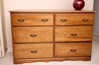 Front view of light brown six-drawer maple dresser with brass bail pulls