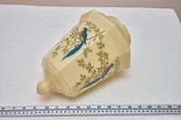 Side view of cream glass shade showing bird and foliage decoration with ruler for scale