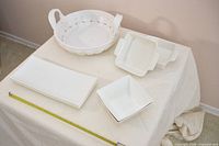 All six white ceramic pieces displayed on table with tape measure for scale