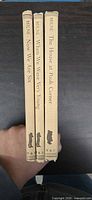Spine view of three tan cloth A. A. Milne hardcovers with titles and silhouettes