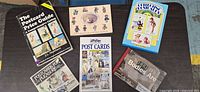 Six paperback postcard related books laid on table