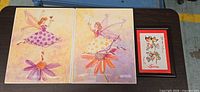 Two fairy prints and framed Sara calligraphy grouped on table