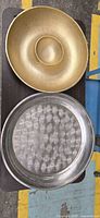 Top view of both items: gold decorative bowl above stainless serving tray