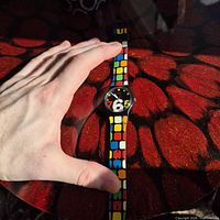 Full view of Swatch wristwatch beside hand for scale