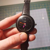 Front view of Timex wristwatch showing black dial and neon hands