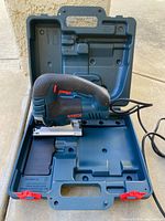Bosch JS470E jig saw seated in fitted plastic case, power cord visible