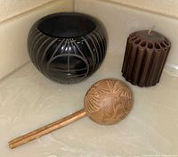 Group shot of candle, black carved jar, wooden maraca