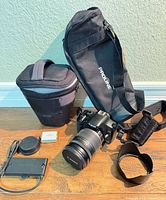 Group image of Canon EOS DSLR with lens, charger, battery, lens hood, rear lens cap, Proline bag, cylindrical lens case