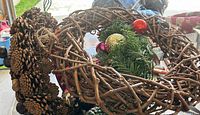 Three different wreaths stacked together: pine cone and chestnut wreath, artificial evergreen wreath with ornaments, bare grapevine wreath