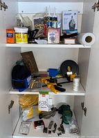 Cabinet with three shelves holding goggles, gloves, sealant tubes, duct seal tub, shelf liner roll, knee pads, hardware items