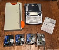 All items in lot: Brother P-Touch label maker, mini guillotine paper cutter, four sealed tape cartridges, manual