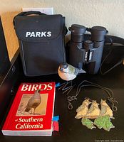Full lot view showing binoculars, case, figurine, book and ornaments