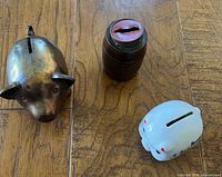 All three coin banks grouped: brass pig, wood barrel, white ceramic pig