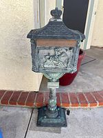 Full view of mailbox on pedestal showing roof, front panel, and overall design